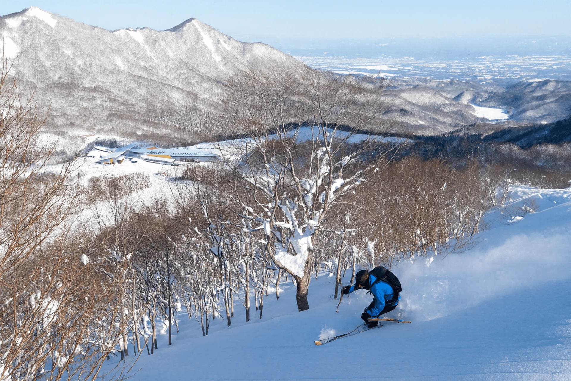 Skier bombing down sidecountry pow with Geto Kogen in the background