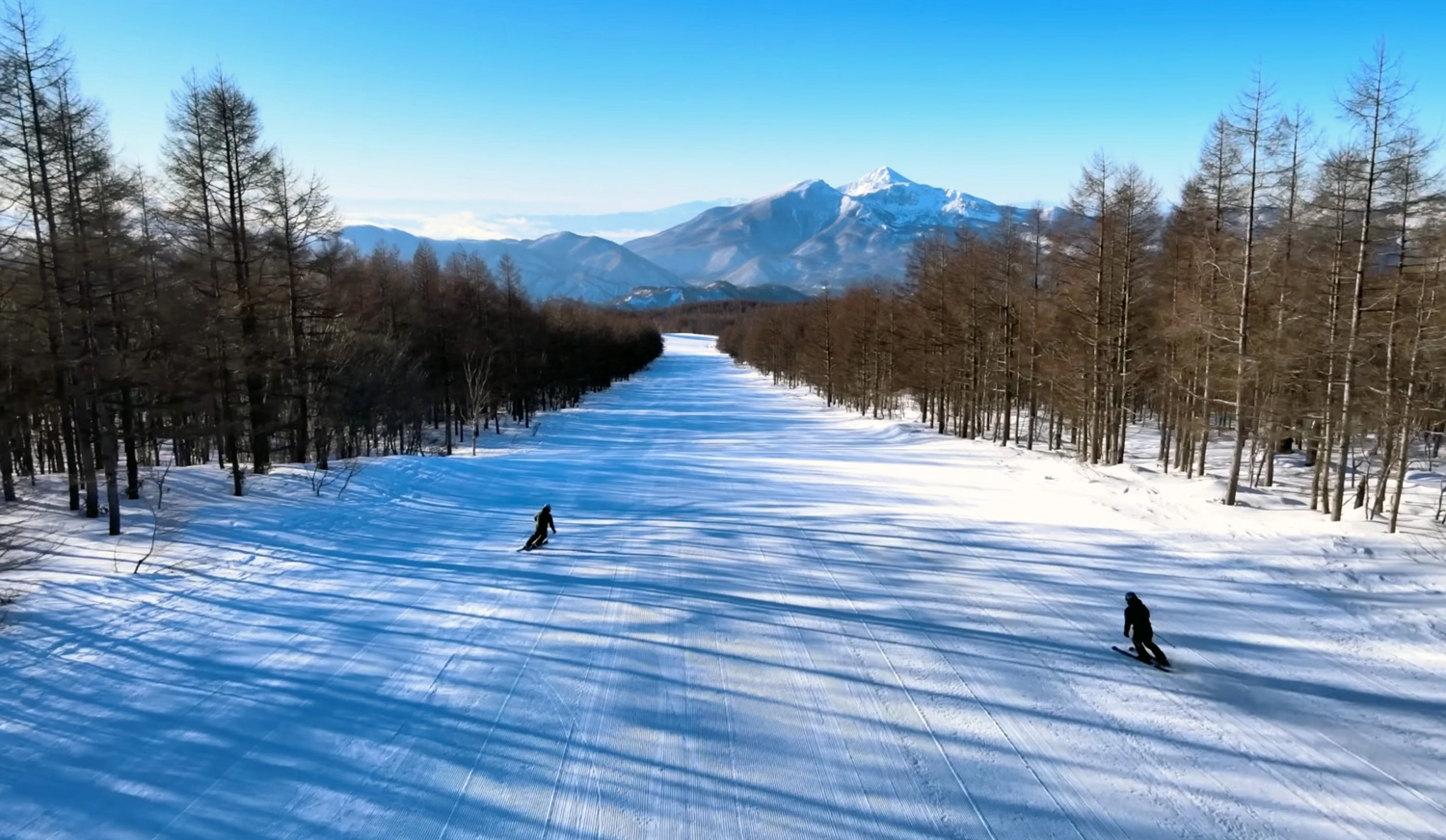 A couple of skiers on a long groomed run at Grandeco