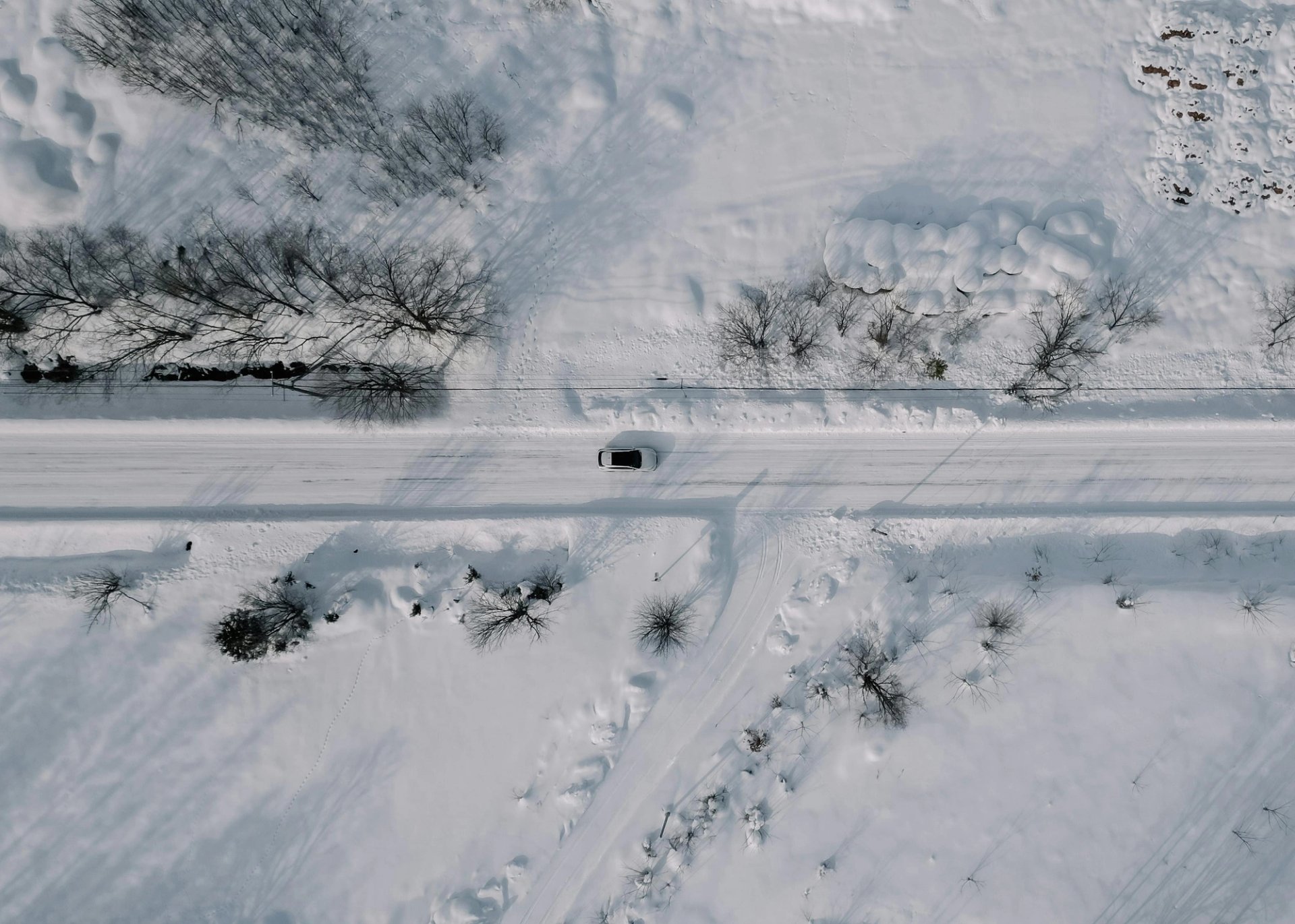 A single car on a snow-covered road, seen from above