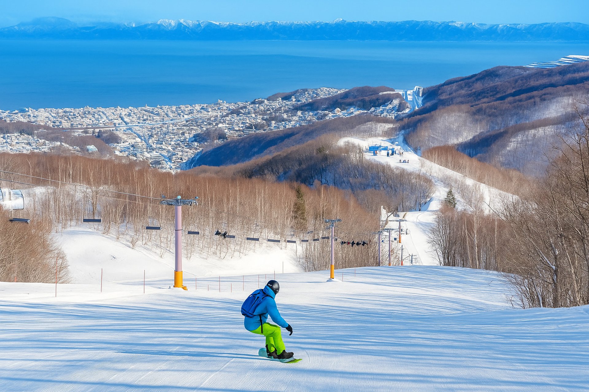 snowboarder flying down a intermediate run looking over Otaru and ocean
