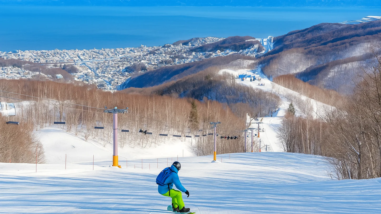 snowboarder flying down a intermediate run looking over Otaru and ocean