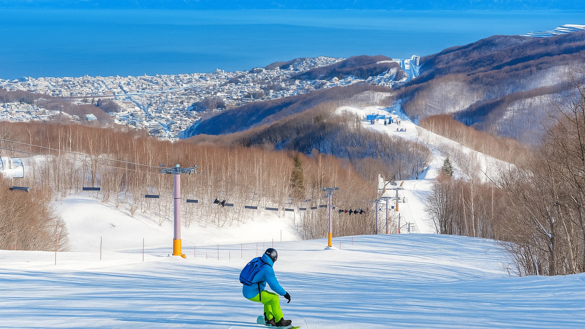 snowboarder flying down a intermediate run looking over Otaru and ocean
