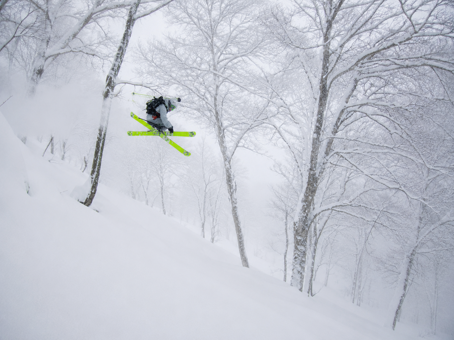 Skier in full send mode in the trees, Japan