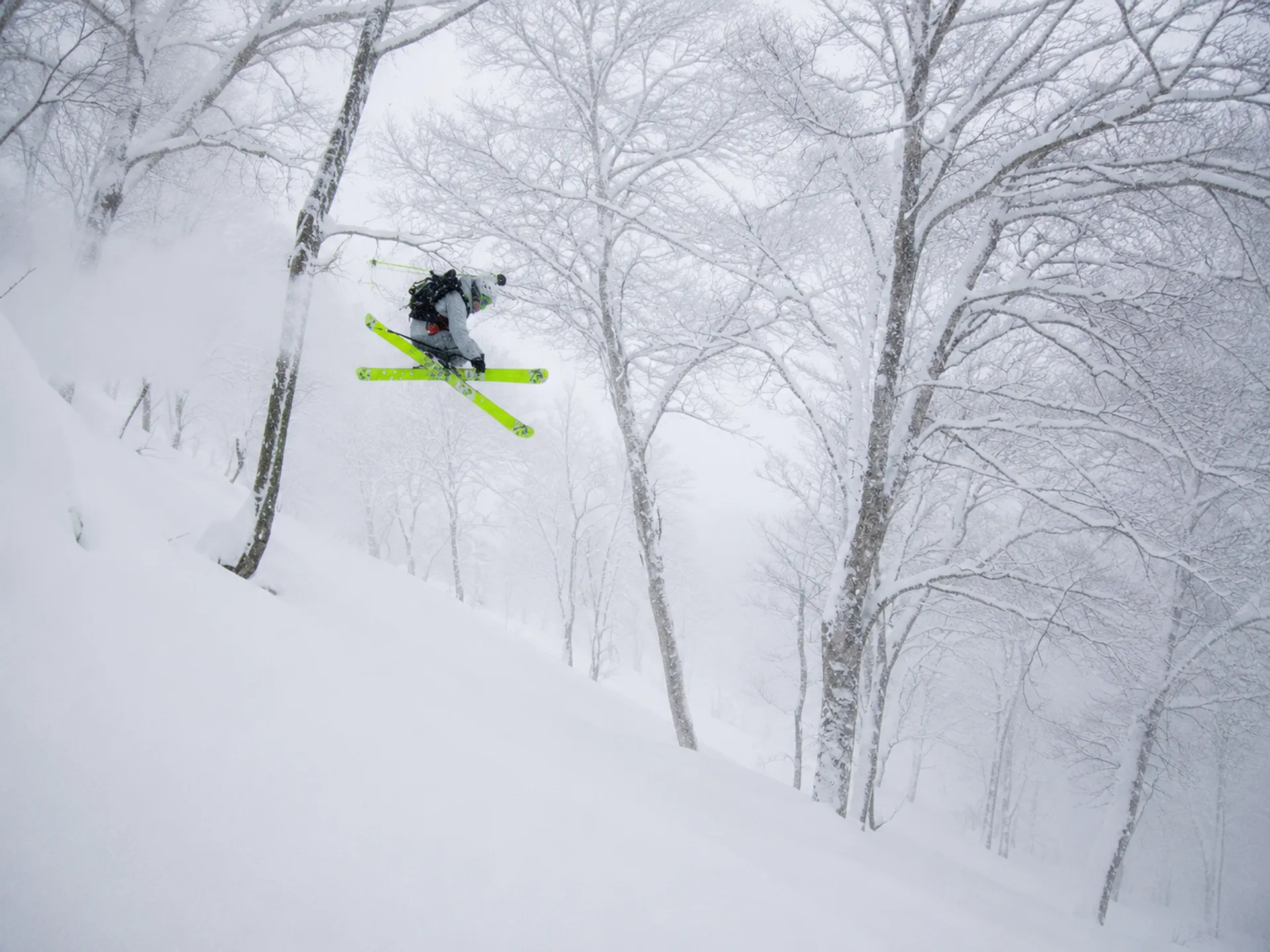 Skier in full send mode in the trees, Japan