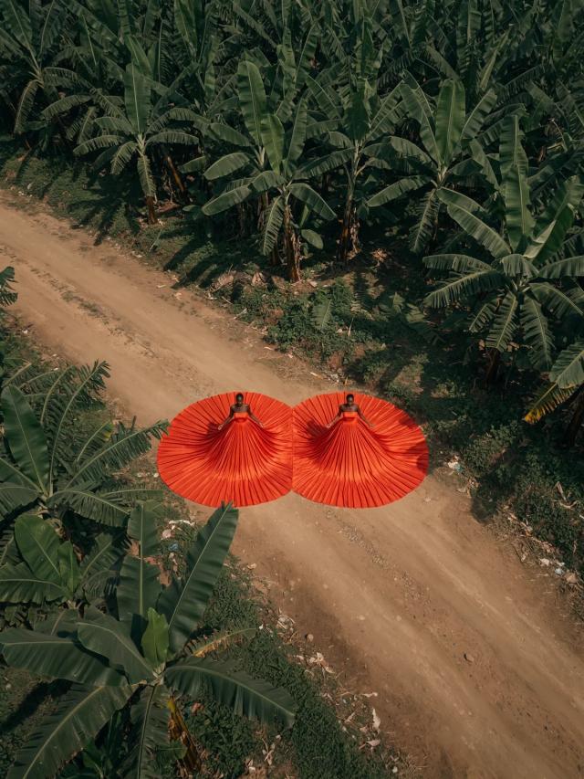 Aerial shot of two red pleated gowns spread across a dirt road