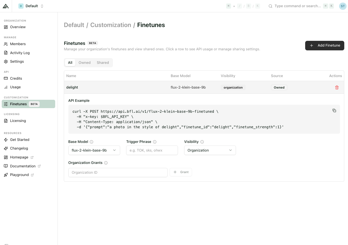 Expanded Finetune detail panel showing the auto-generated curl API example plus editable Base Model, Precision, Trigger Phrase, and organization sharing fields