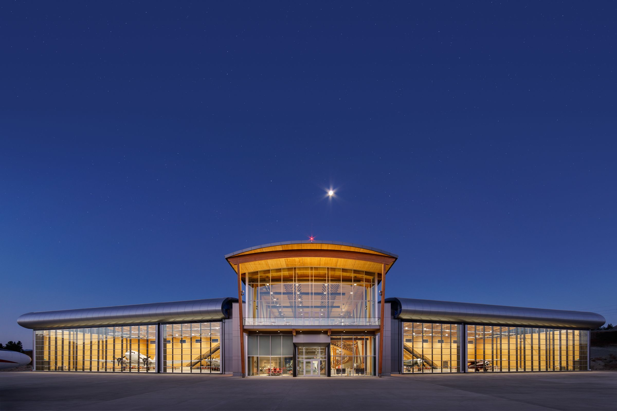 The front of the KF Centre of Excellence in Kelowna, BC, lit up under a night sky.