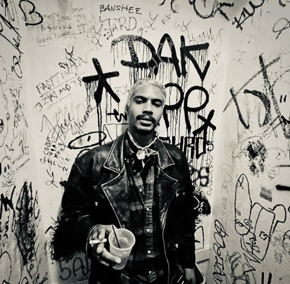 Portrait of Mathieu against a graffiti-covered wall