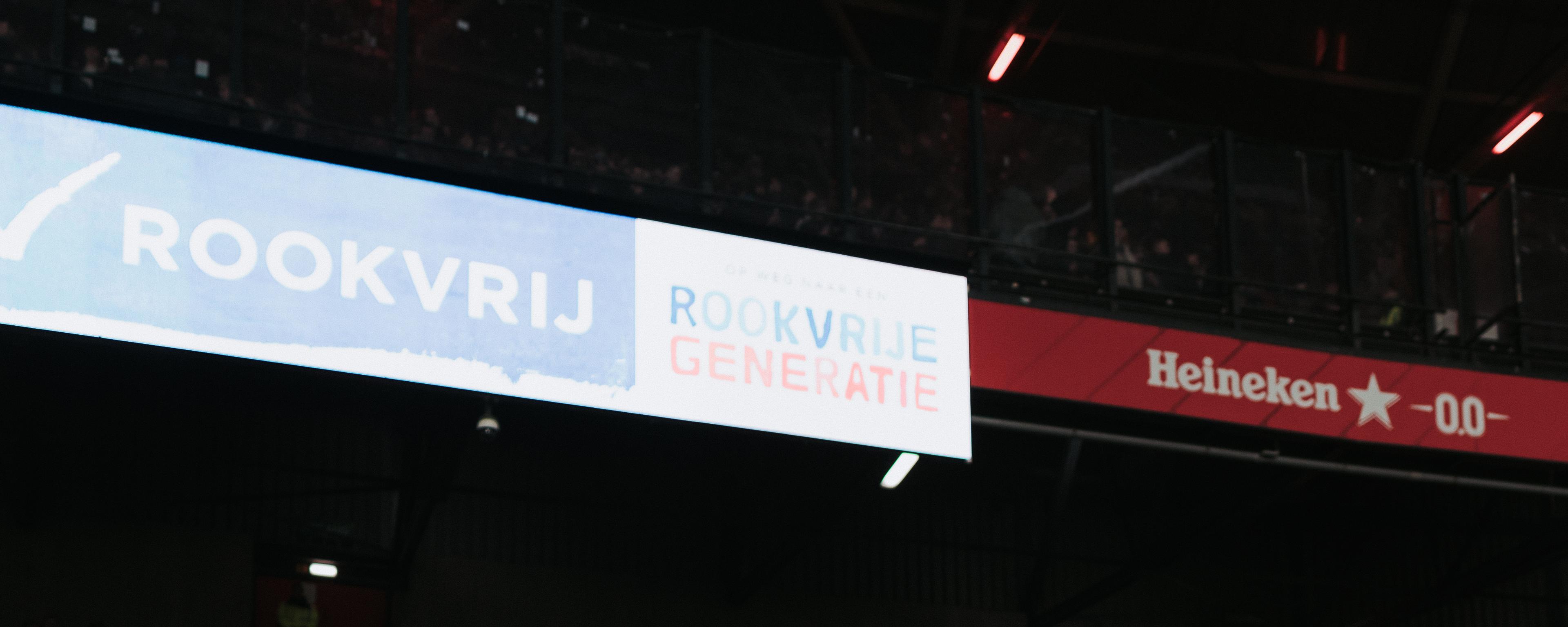 Twee supporters in De Kuip onder een uiting van een Rookvrije Generatie