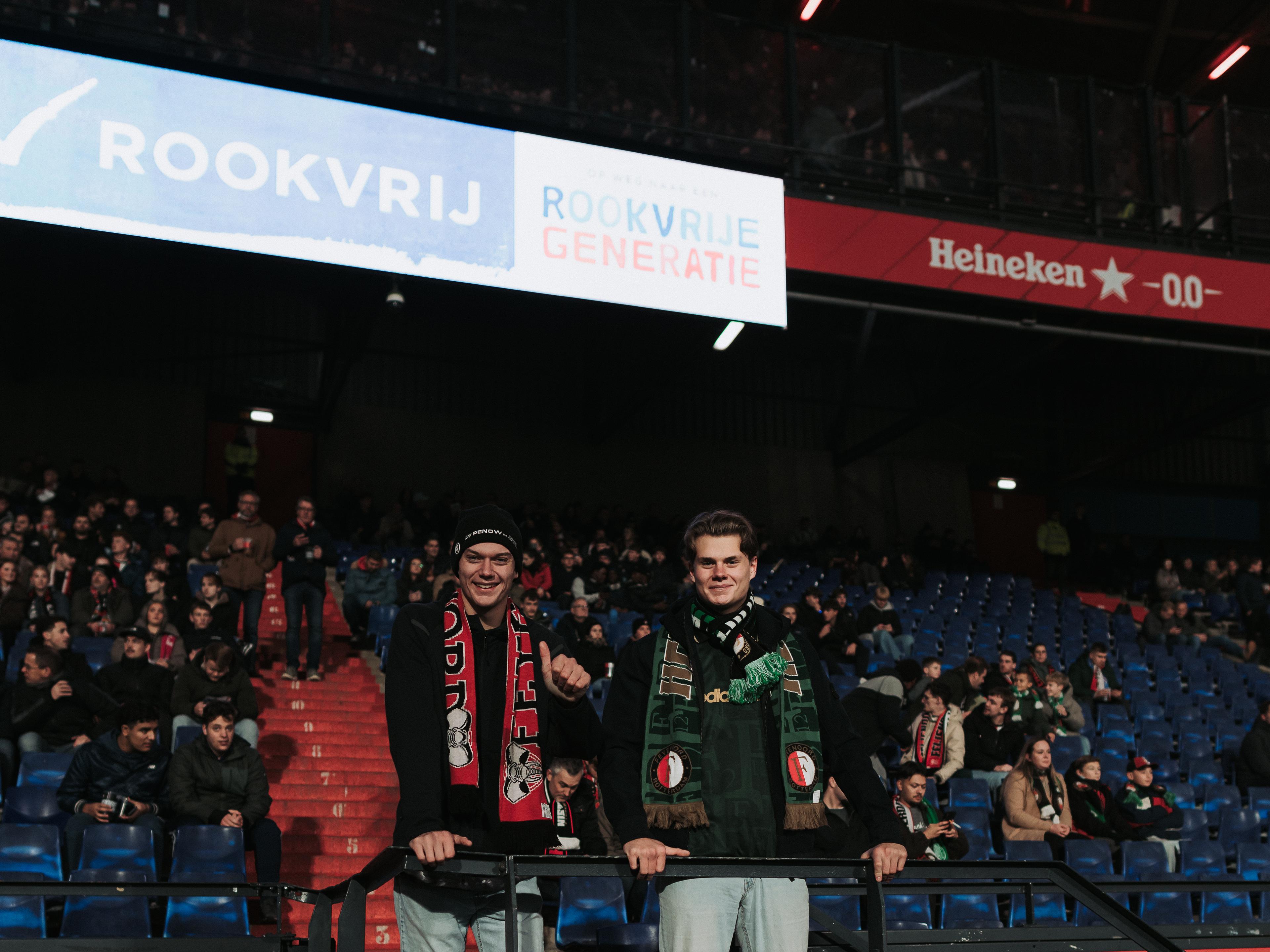 Twee supporters in De Kuip onder een uiting van een Rookvrije Generatie