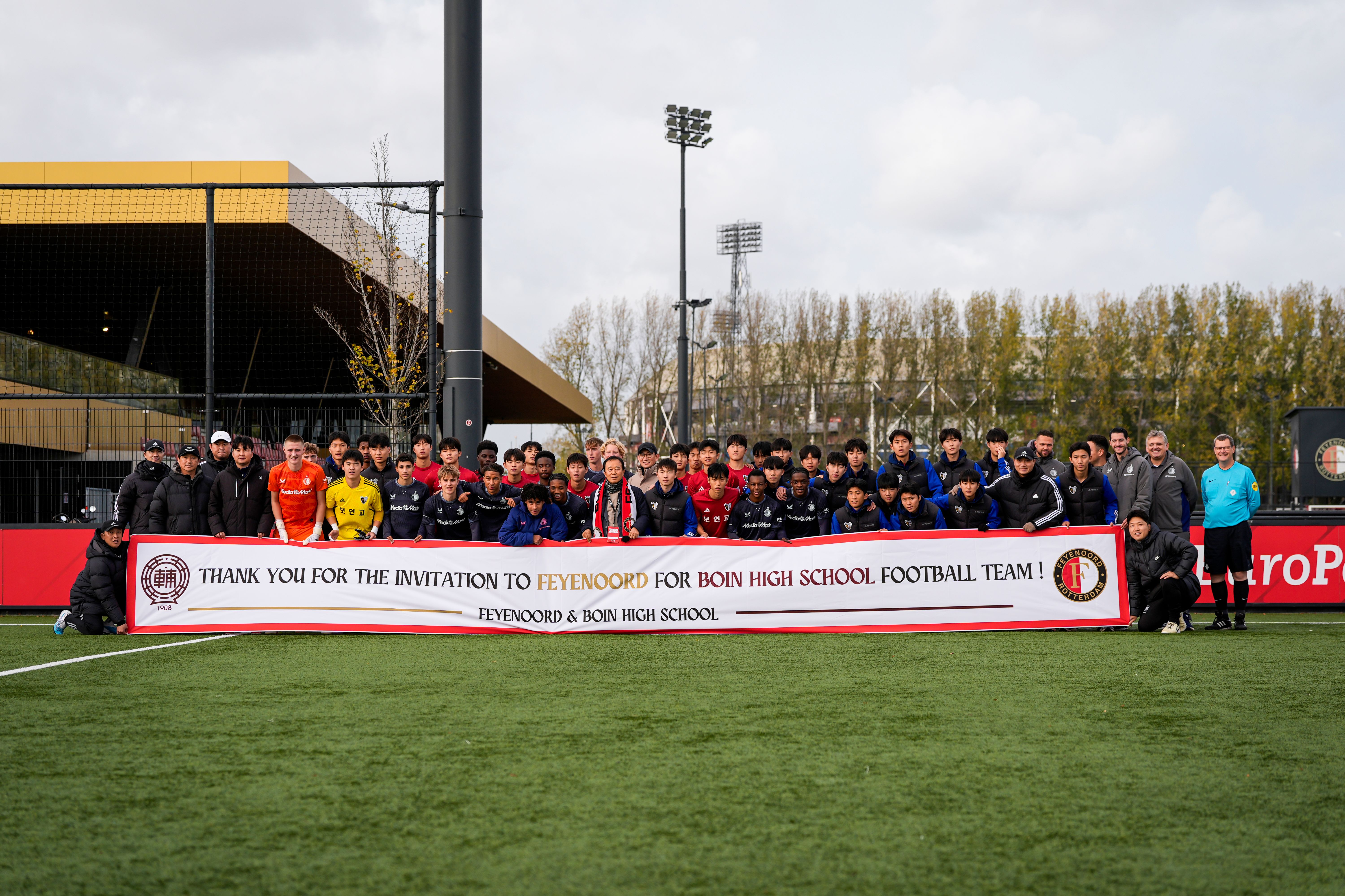Foto van Feyenoord O17 gemengd met Boin Highschool O17 en houden een banner vast met bedankt voor de uitnodiging.