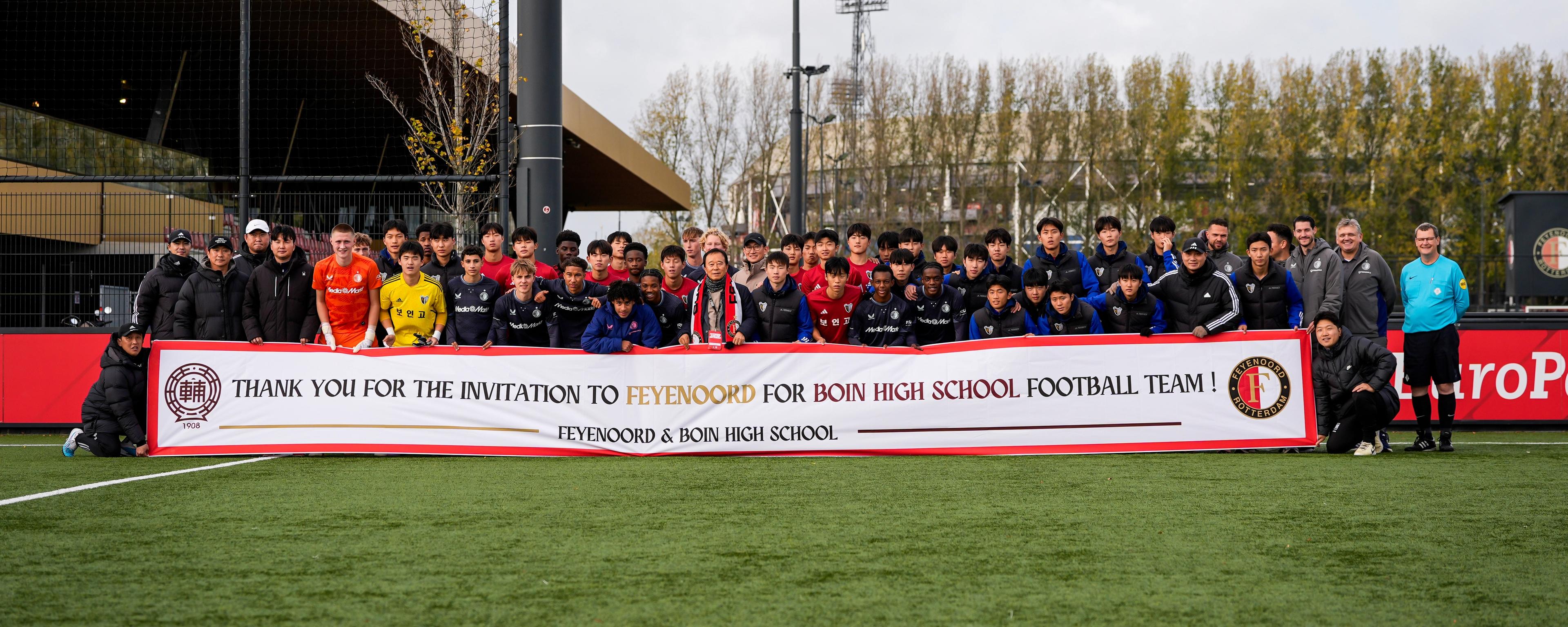 Foto van Feyenoord O17 gemengd met Boin Highschool O17 en houden een banner vast met bedankt voor de uitnodiging.
