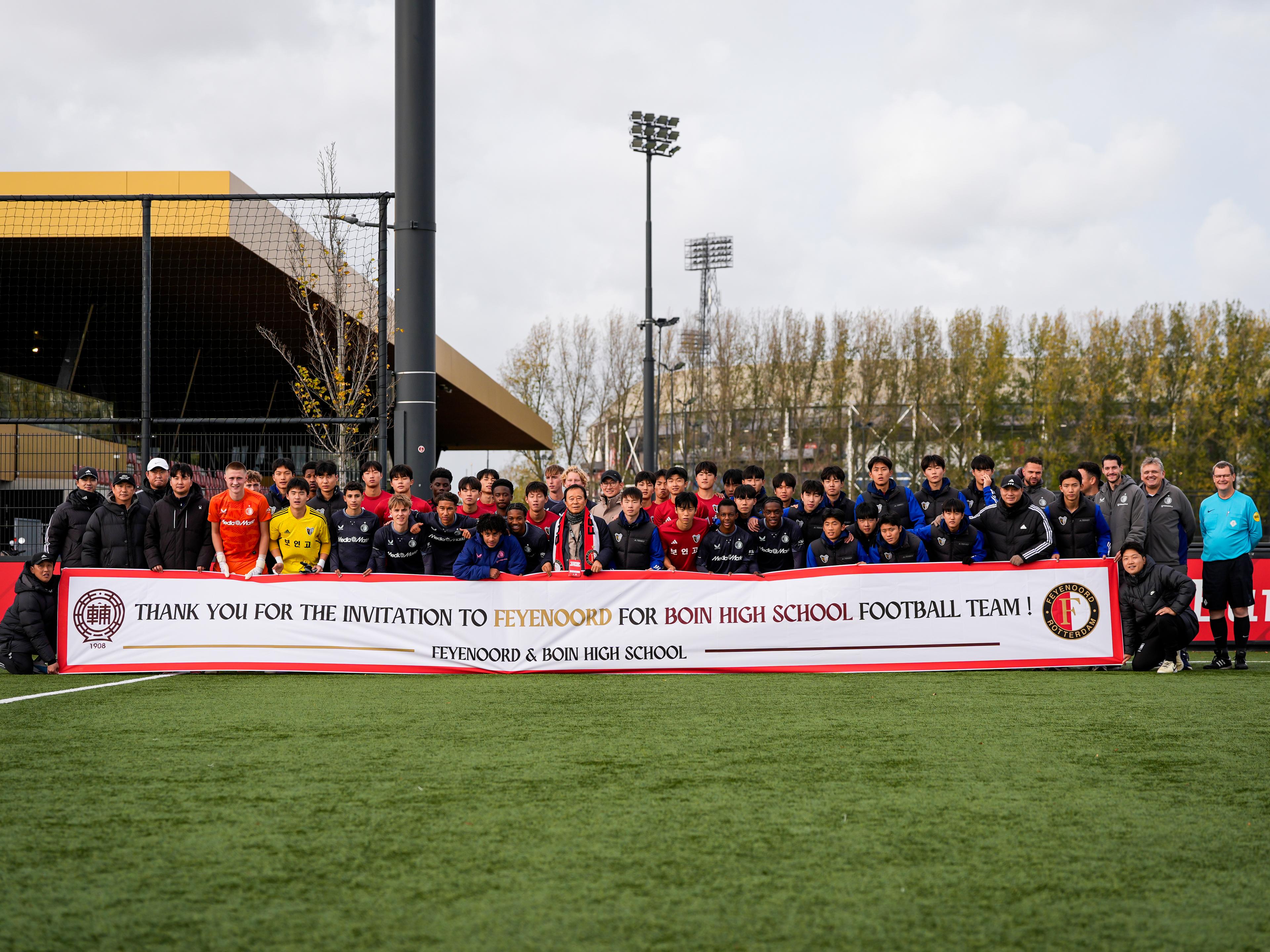 Foto van Feyenoord O17 gemengd met Boin Highschool O17 en houden een banner vast met bedankt voor de uitnodiging.
