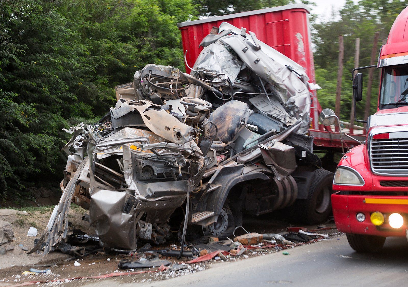 red truck collided with a silver car on a highway both are smashed up and badly damaged