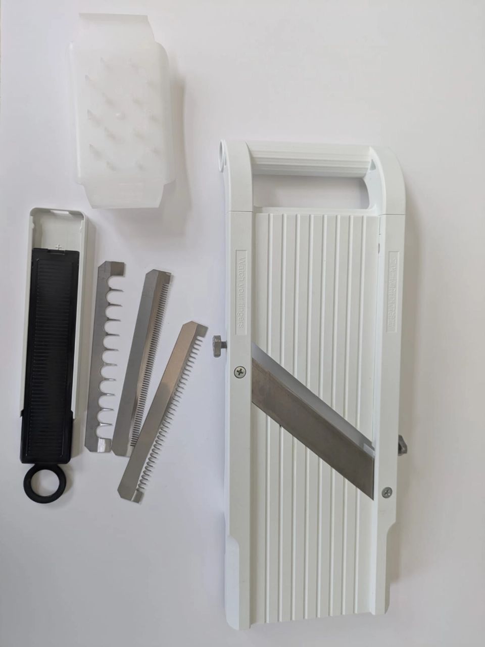 Super Benriner No. 95 mandoline with finger guard and three interchangeable julienne blades on a white surface