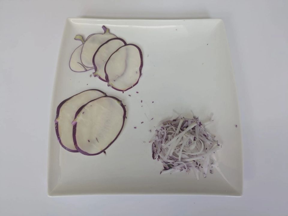 Kohlrabi sliced at two thicknesses and cut into fine julienne on a white plate