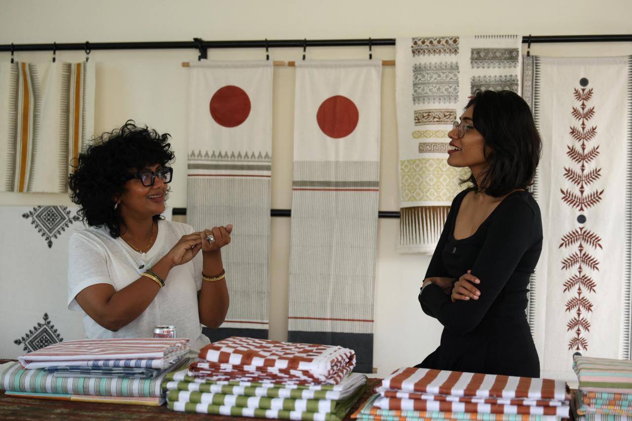 Two people talking in a showroom hung with block-printed textiles