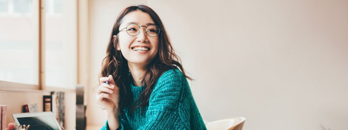 Smiling woman in a teal sweater and glasses.