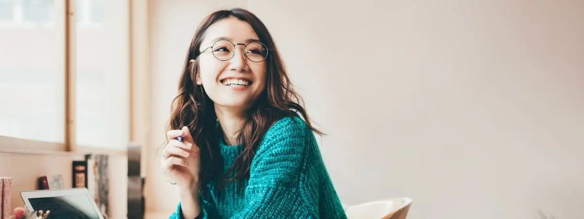 Smiling woman in a teal sweater and glasses.