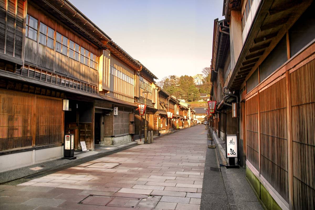 Traditional Japanese street lined with old wooden buildings, stone pavement, and lanterns.