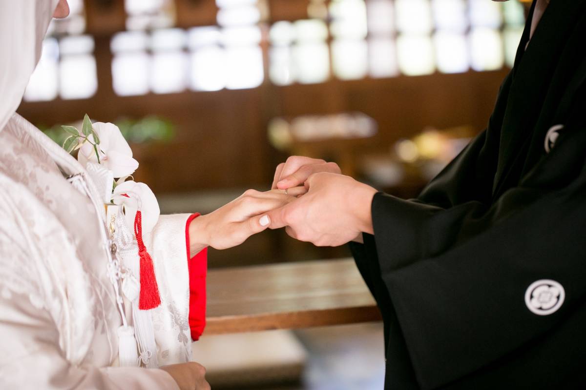 A couple in traditional Japanese wedding attire holding hands.