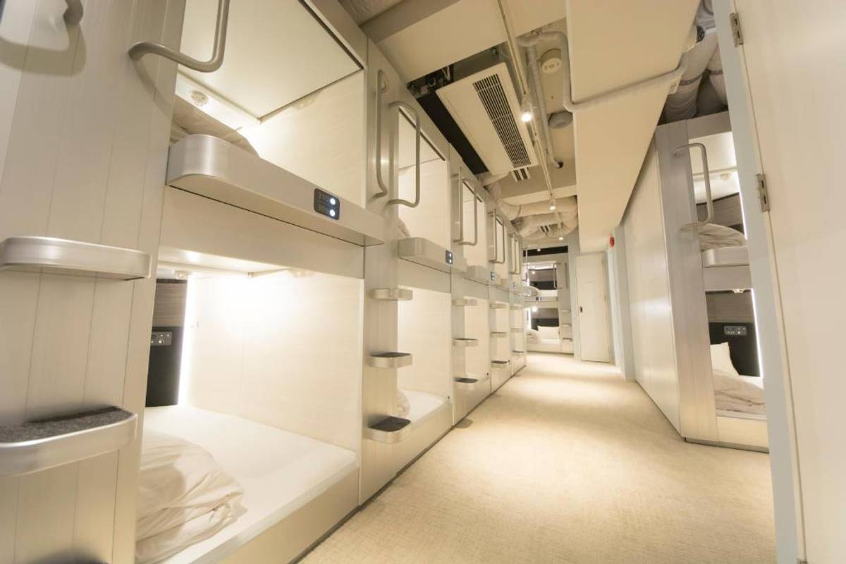 Hallway of a modern capsule hotel lined with individual sleeping pods.
