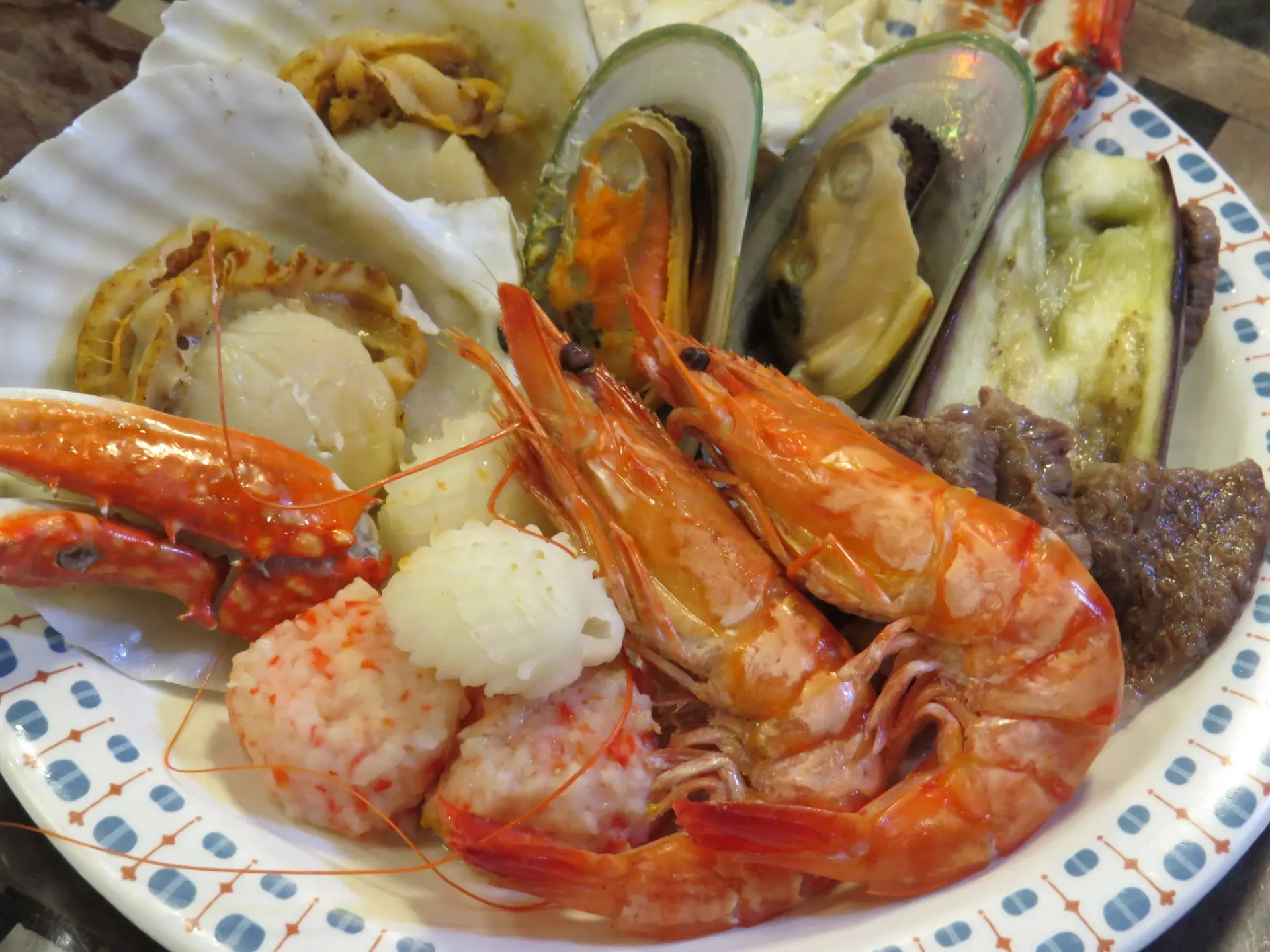 A plate of shrimp, scallops, mussels, crab, and other seafood with eggplant and meat.