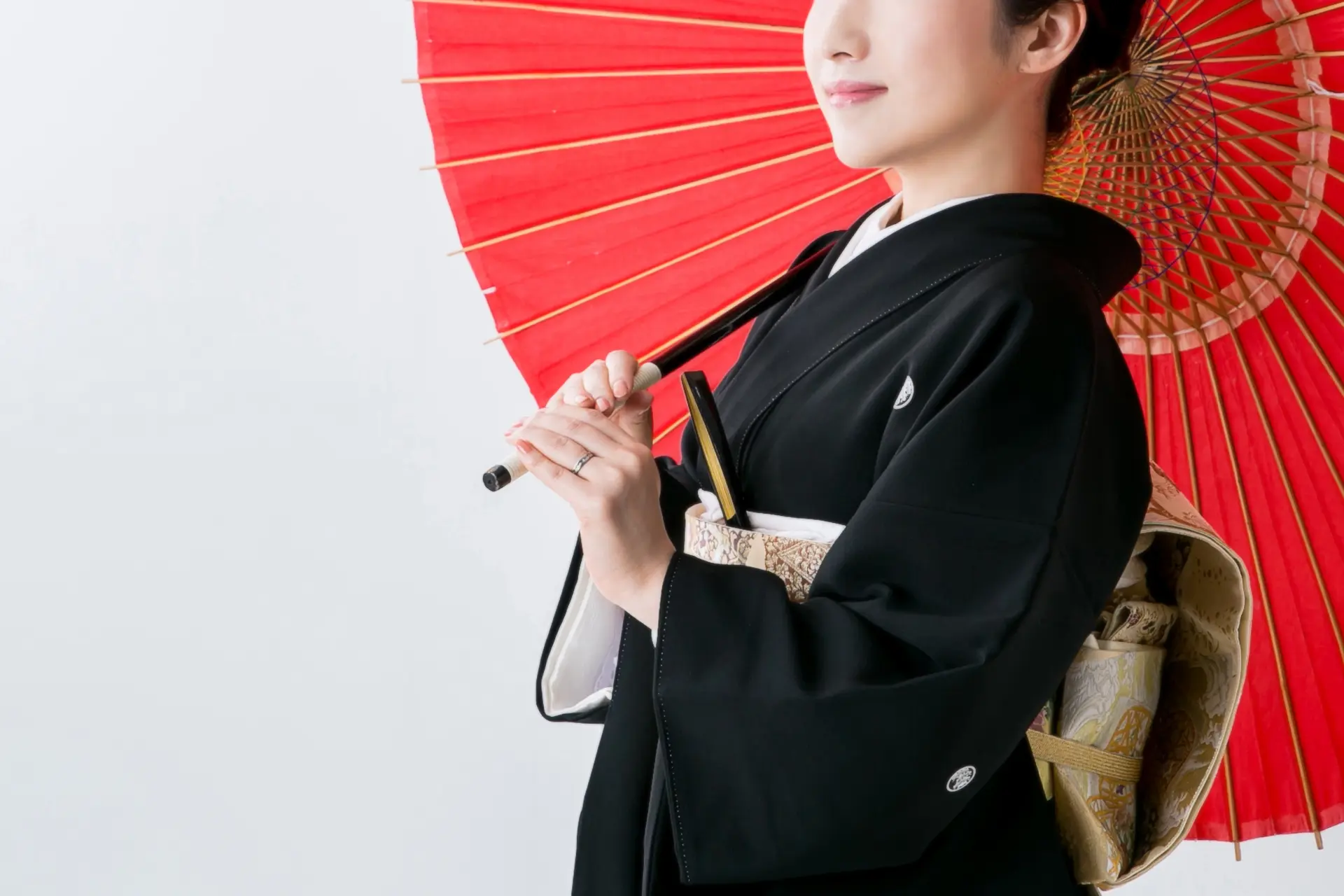Woman in a black kimono holding a red Japanese umbrella.