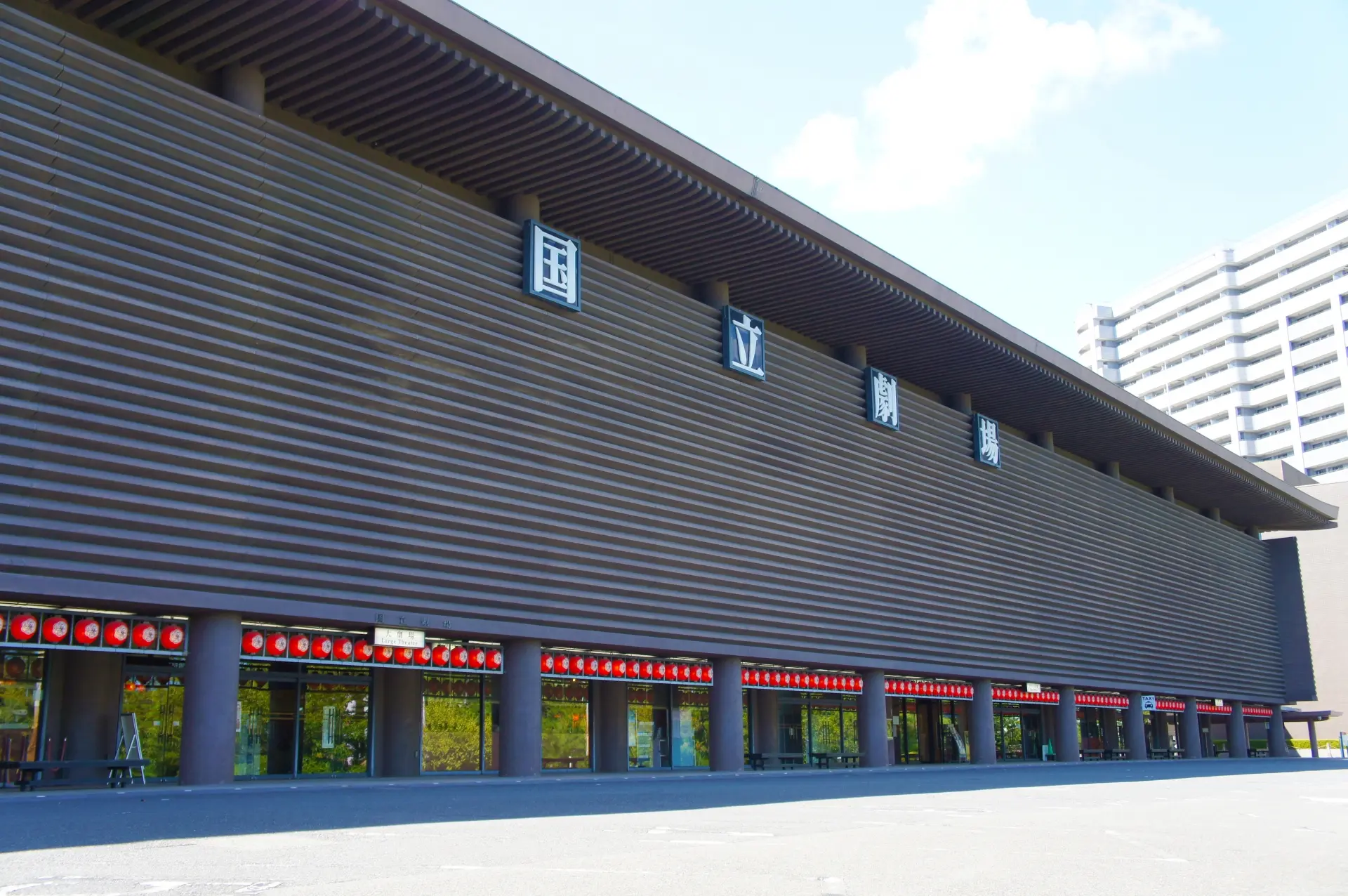 National Theatre building with a dark ribbed facade, Japanese characters, and red lanterns.