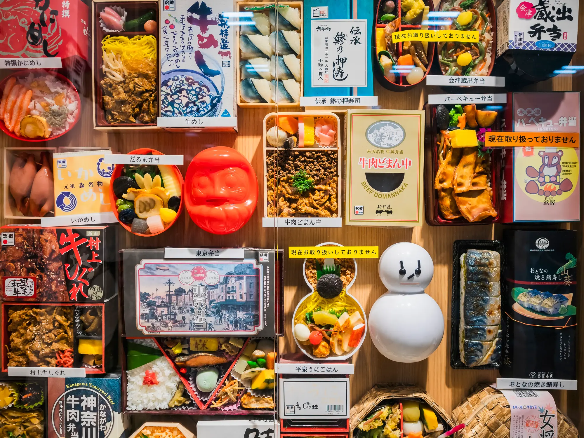 A retail display shows a wide variety of Japanese bento boxes and pre-packaged meals