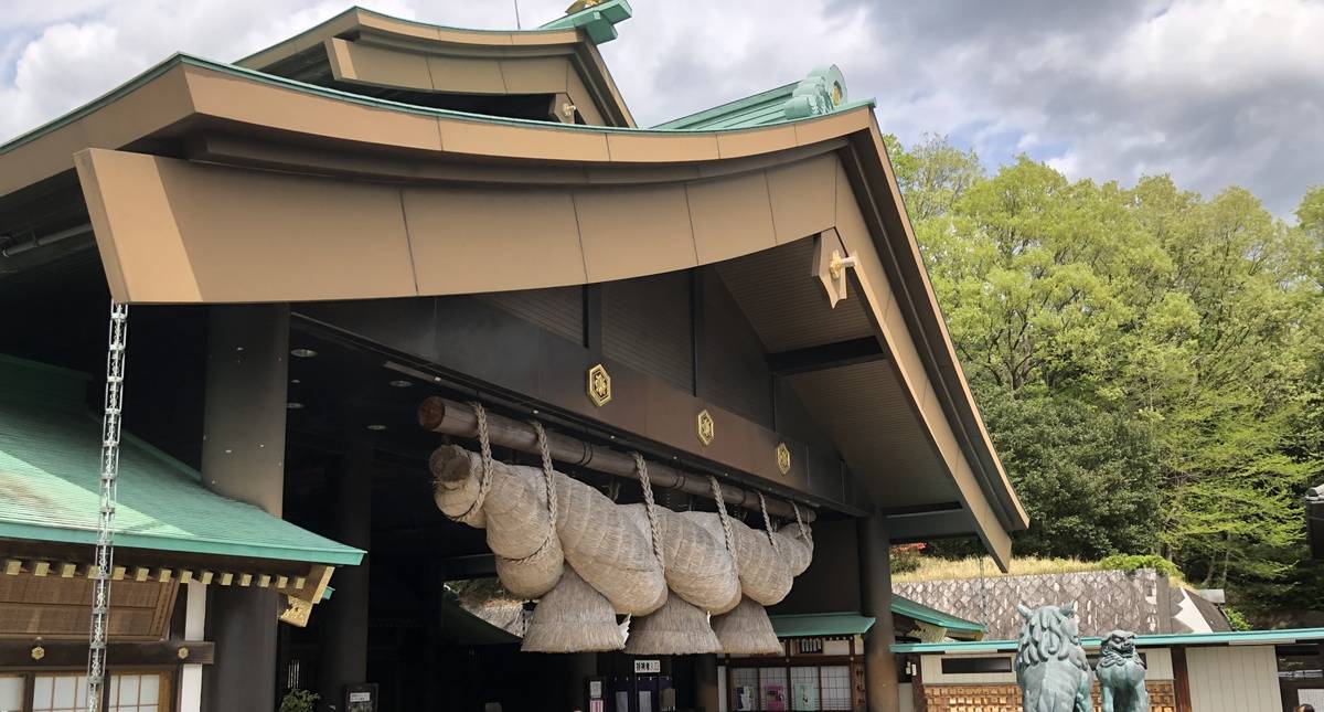 Japanese shrine entrance with a large shimenawa and guardian statues.