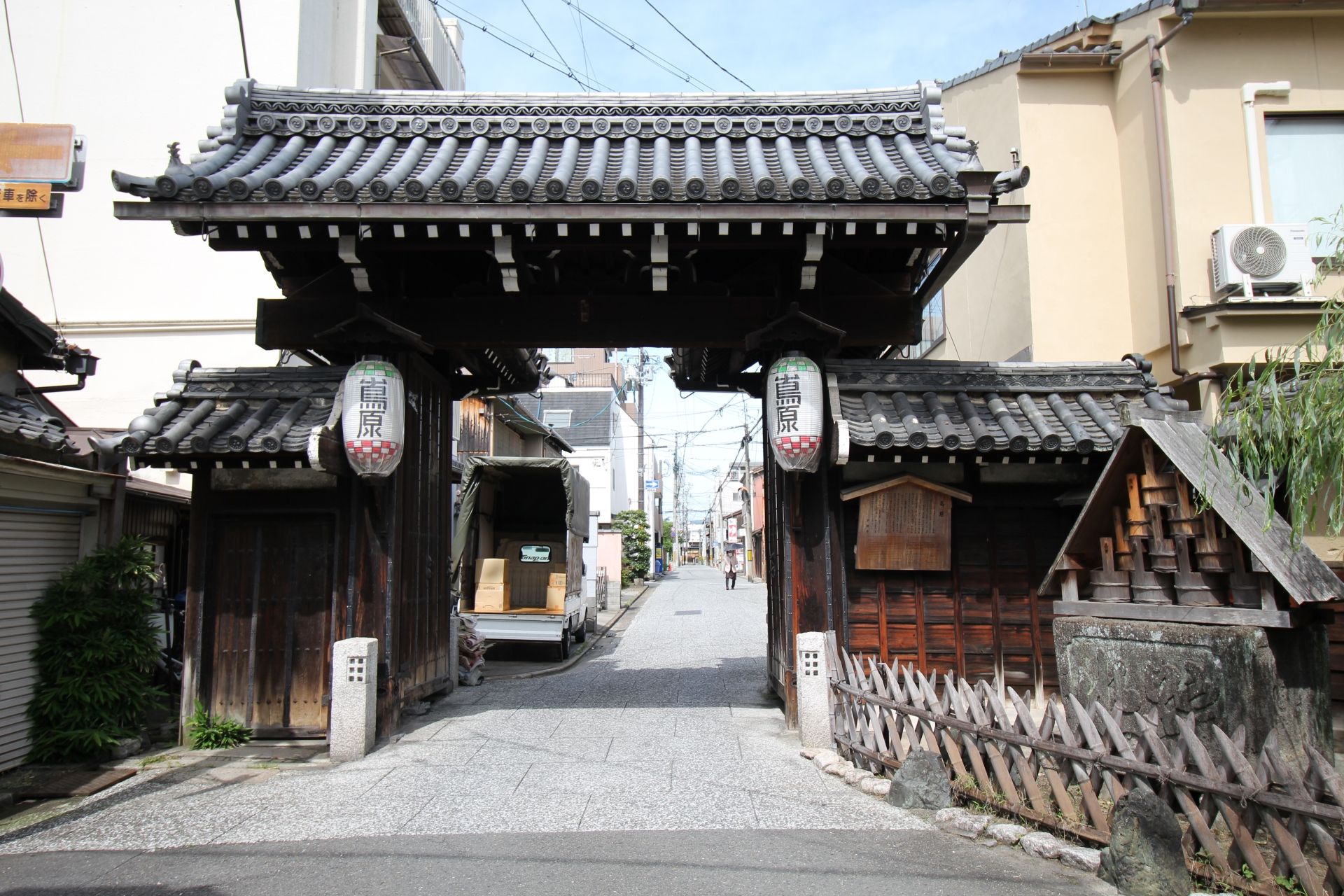 Traditional Japanese gate with lanterns spanning a narrow street.