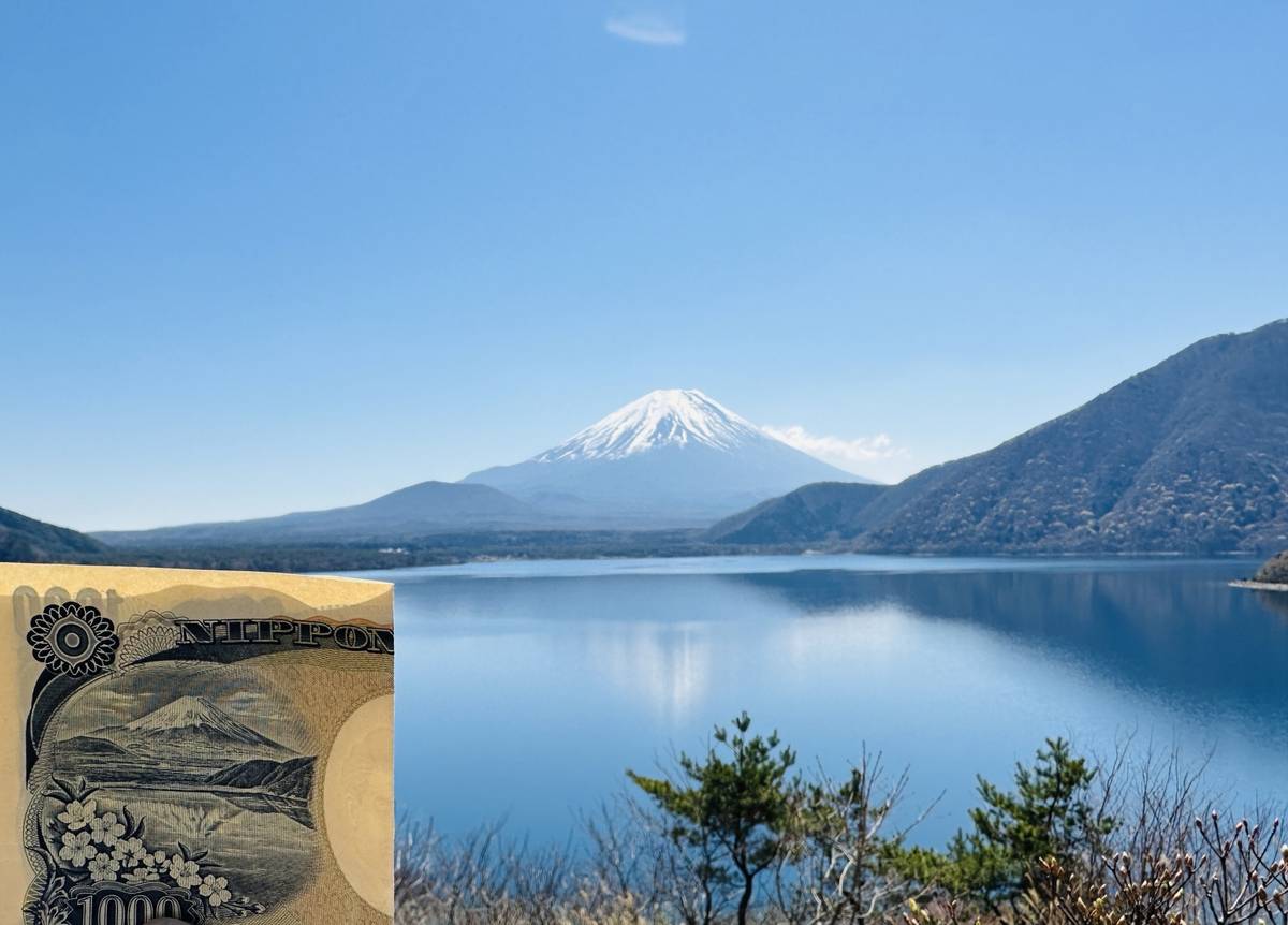 A scenic view of snow-capped Mount Fuji and a lake, with a Japanese 1000 yen banknote featuring the same scene partially visible in the foreground.