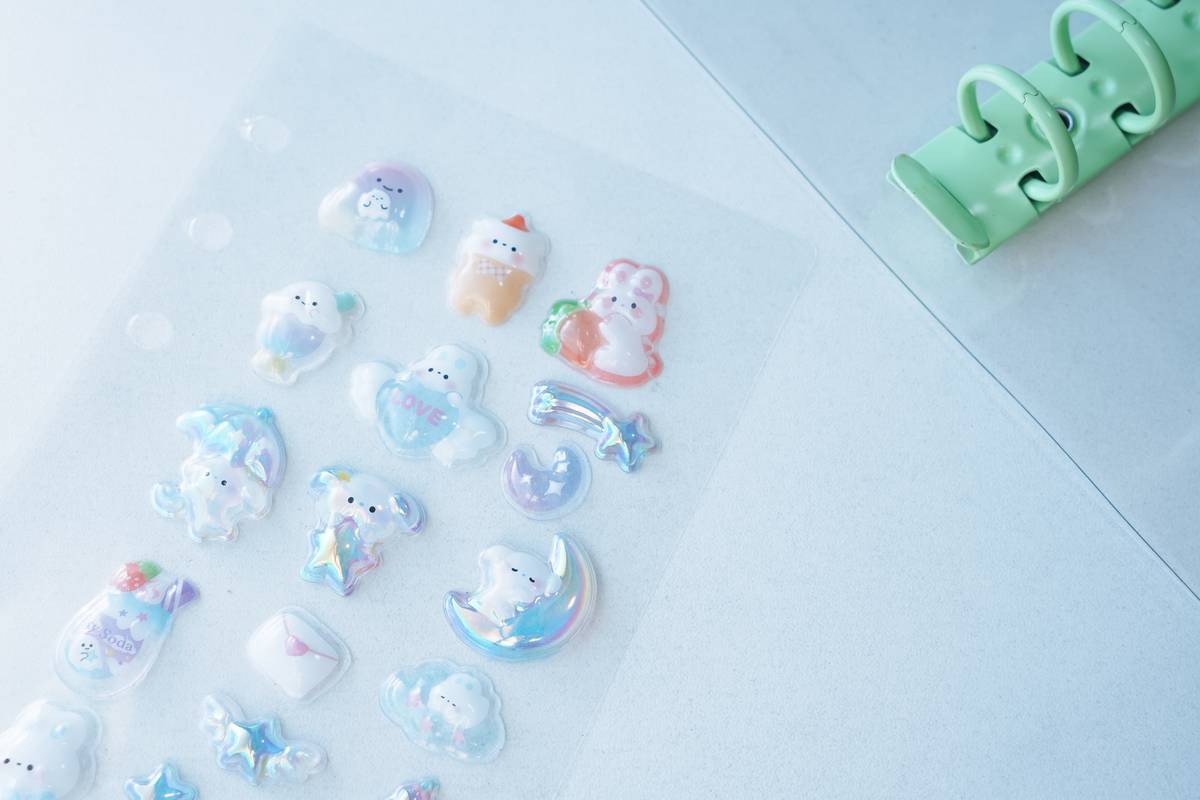 Iridescent pastel puffy stickers on a clear binder insert next to a green binder mechanism.