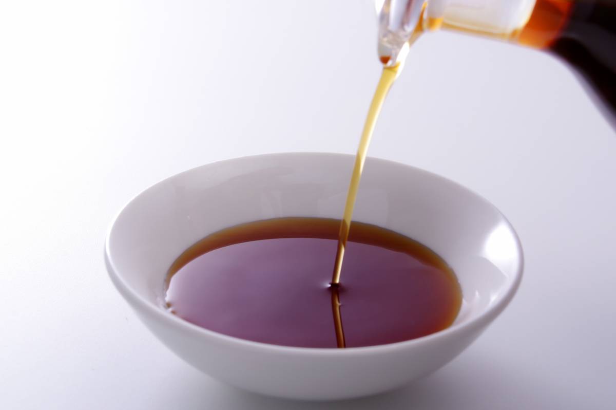 Soy sauce being poured into a white bowl.