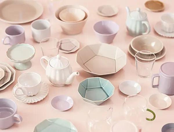 A top-down shot of various pastel dishes and drinkware, including teapots, plates, bowls, and mugs