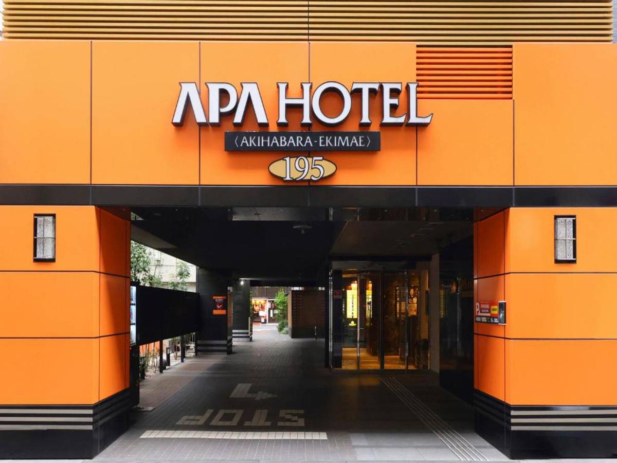APA Hotel entrance with an orange facade, black trim, and "APA HOTEL (AKIHABARA - EKIMAE) 195" signage.