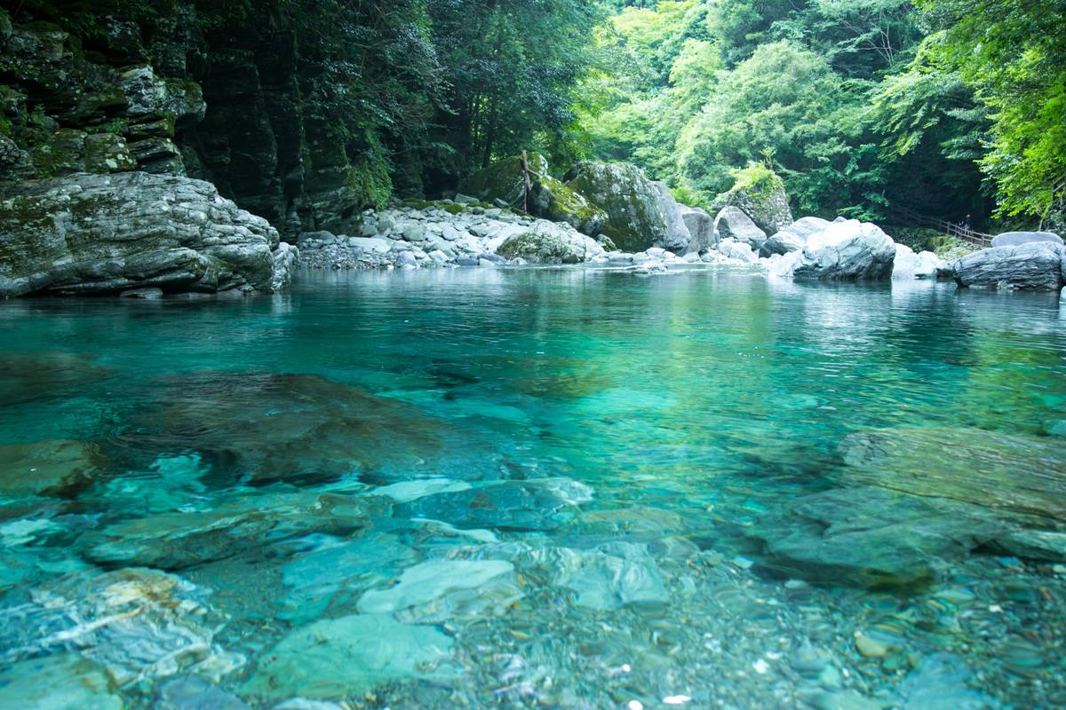Clear turquoise river flowing through a rocky forest.