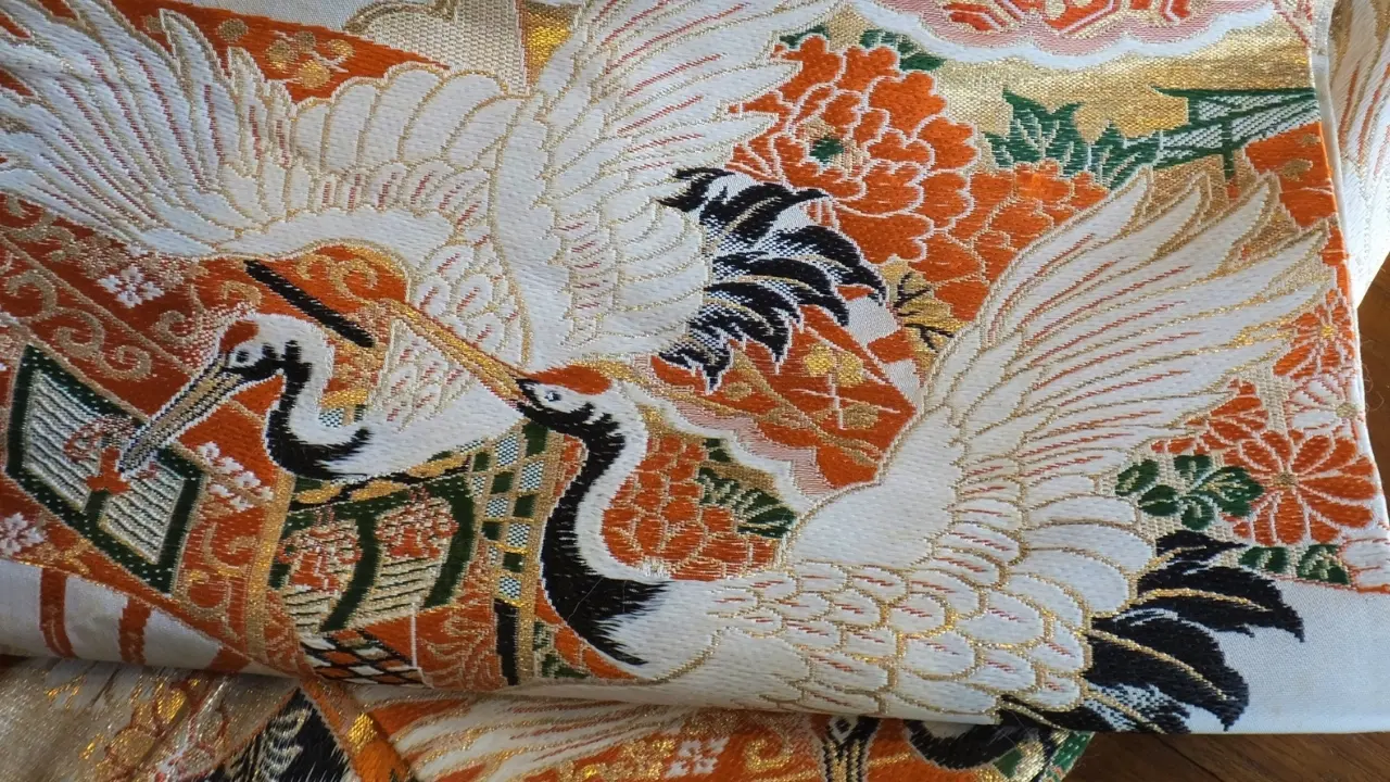 Ornate Japanese textile with red-crowned cranes, orange flowers, and gold patterns.