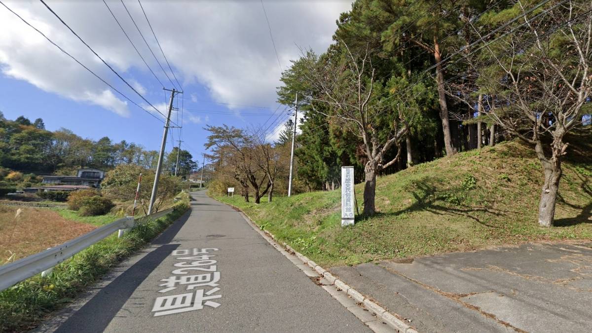 a road with trees on the side of it and a sign on the side of the road .
