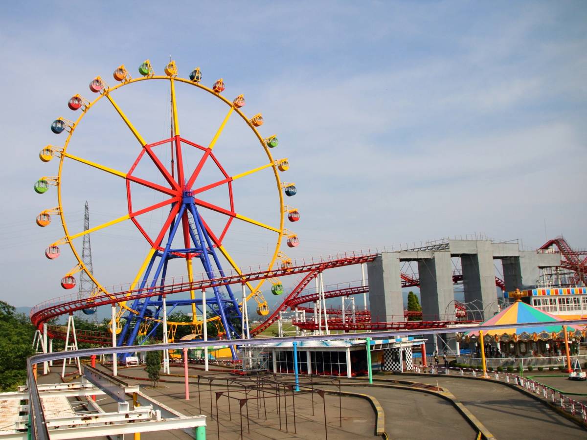 A colorful Ferris wheel and red roller coaster in an amusement park.