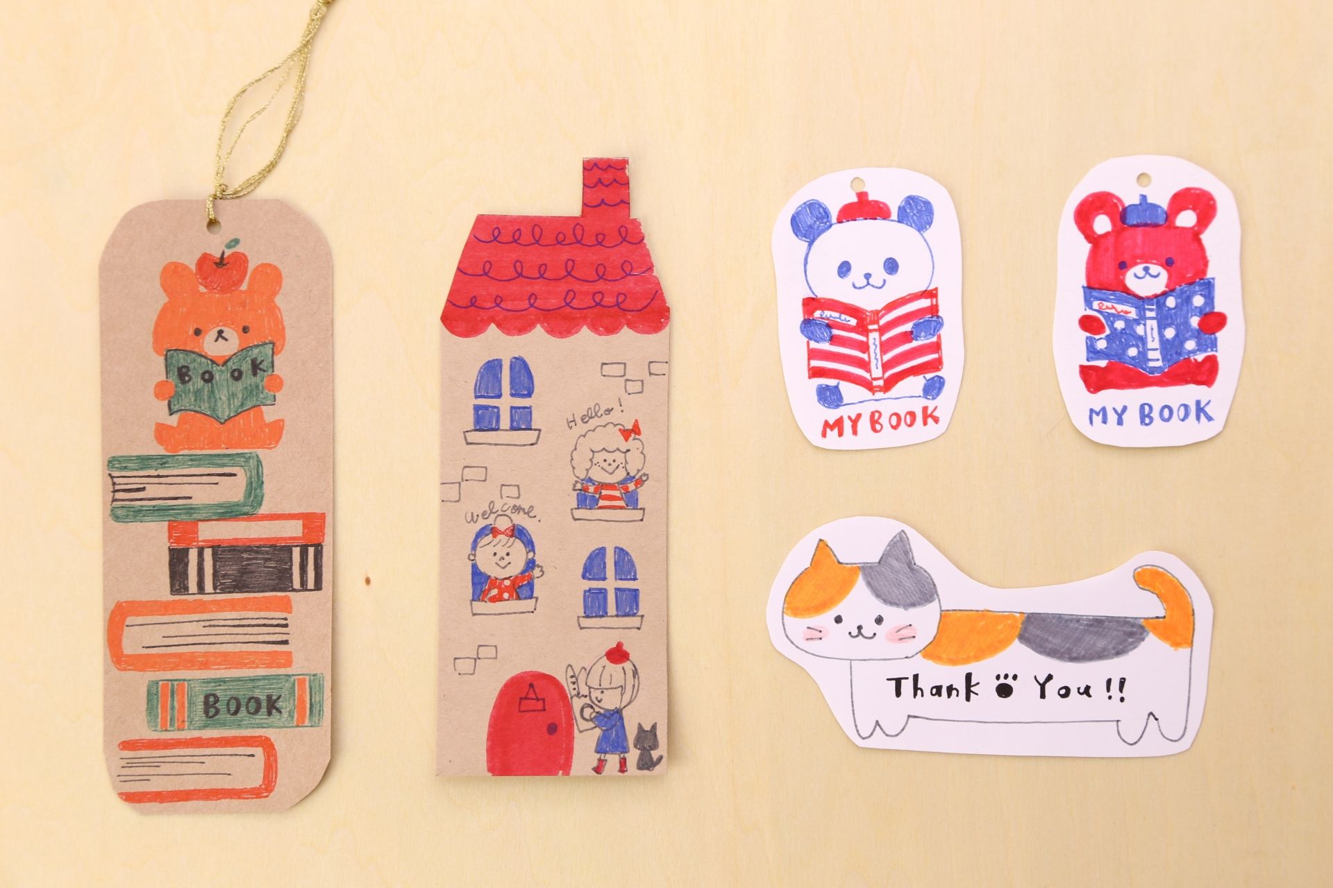 Handmade paper crafts including a bear bookmark, a house, two bear cutouts reading books
