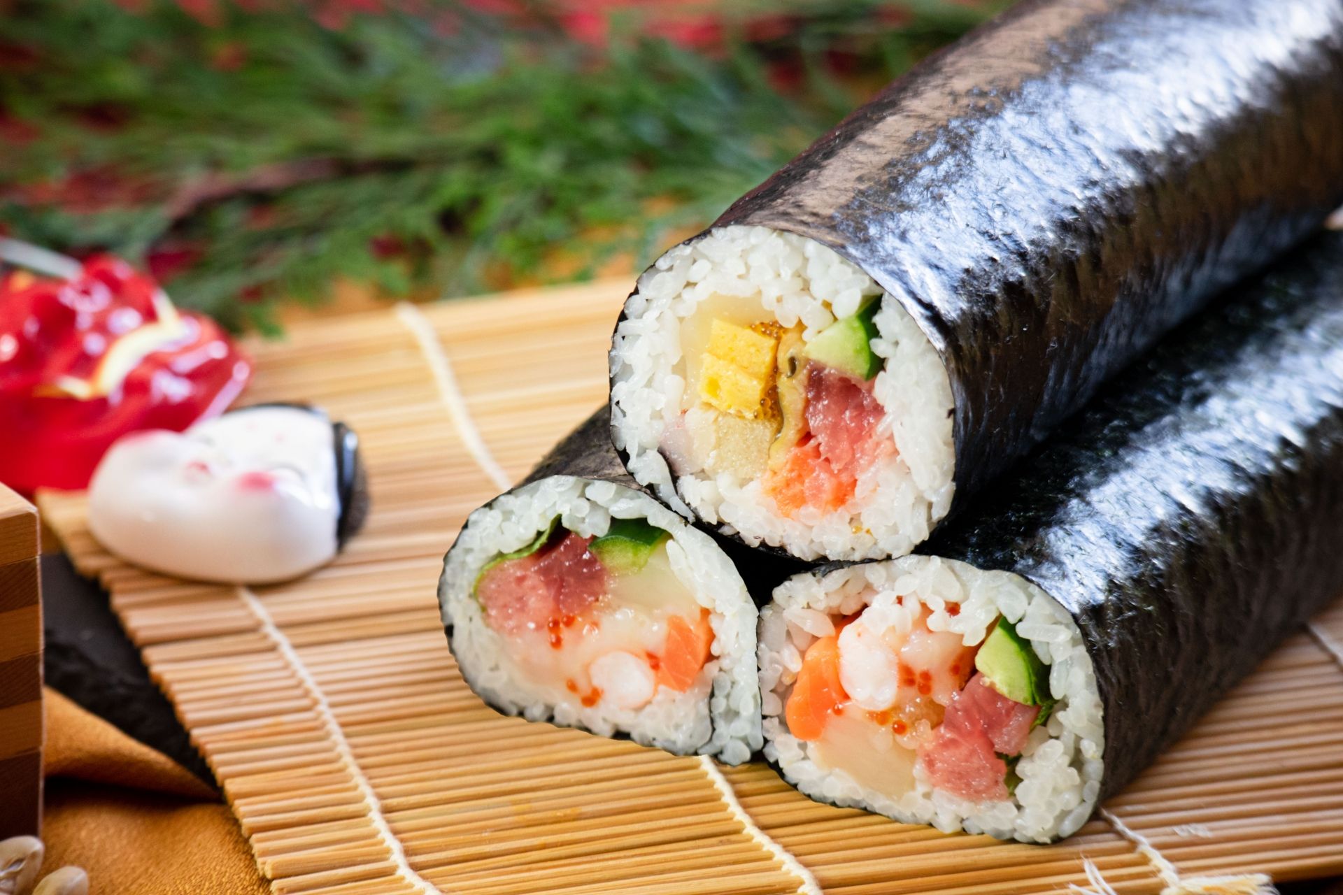 Sushi rolls filled with fish, shrimp, and vegetables, on a bamboo mat.