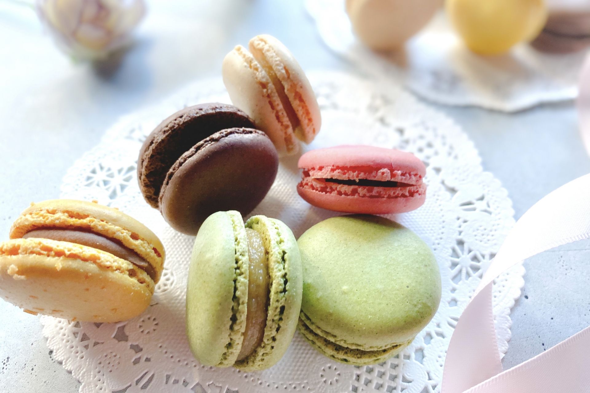 Assorted macarons in chocolate, pink, green, and cream on white doilies.