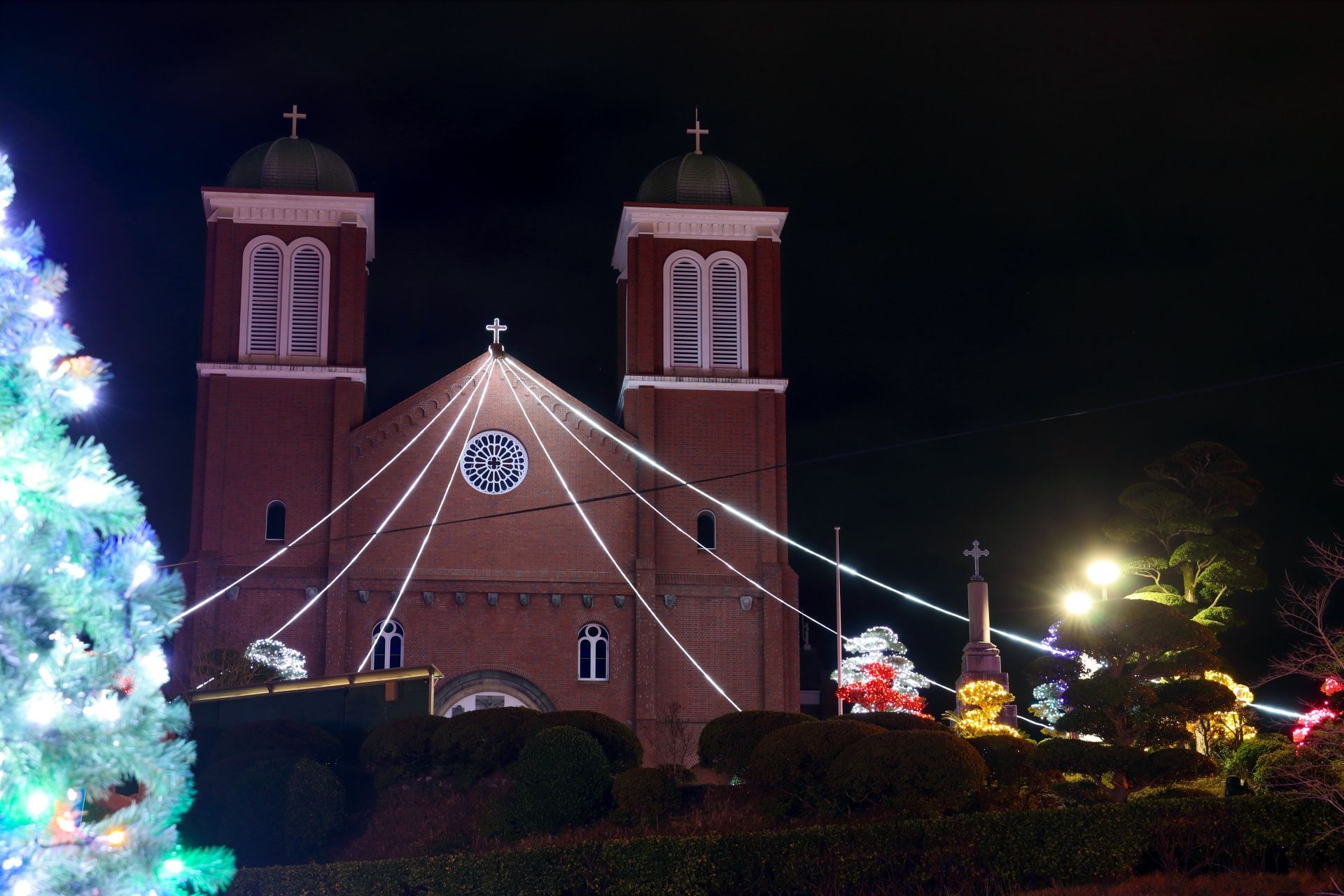 A church and surrounding landscape decorated with Christmas lights at night.