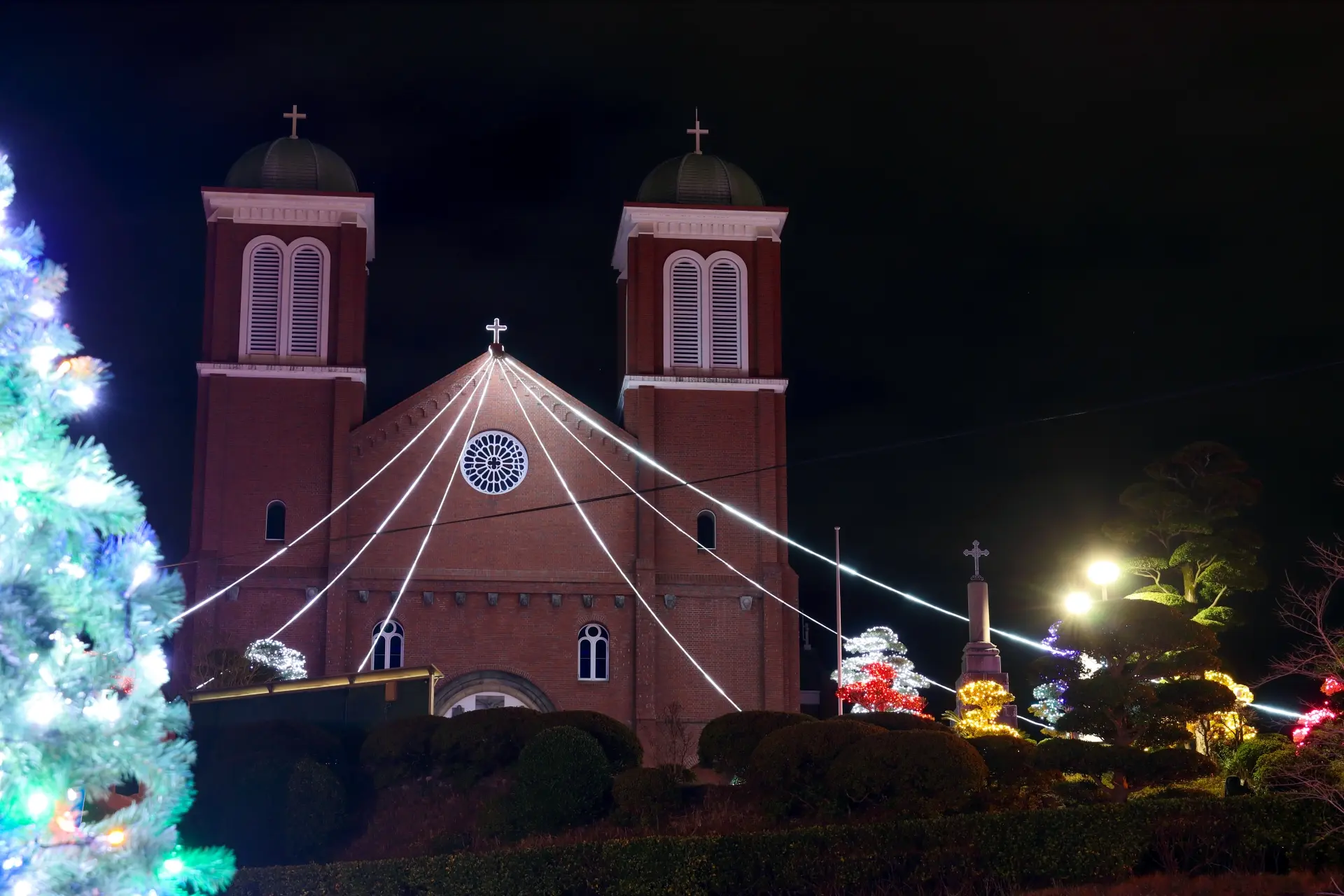 A church and surrounding landscape decorated with Christmas lights at night.