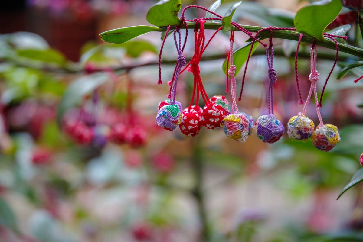 Colorful patterned fabric balls hanging from a green branch.