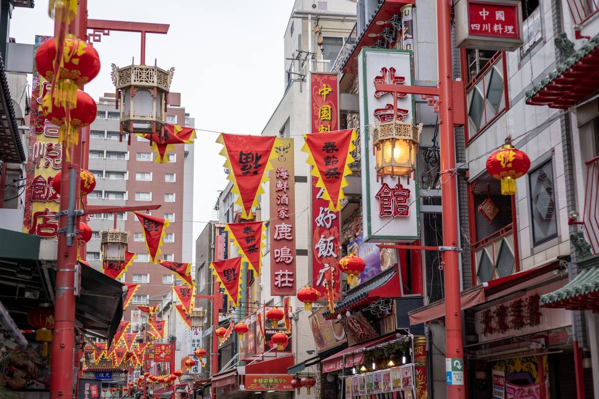 A street decorated with red and yellow Chinese lanterns, flags, and ornate lampposts.