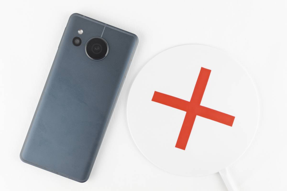 A dark gray smartphone next to a white paddle with a red X.