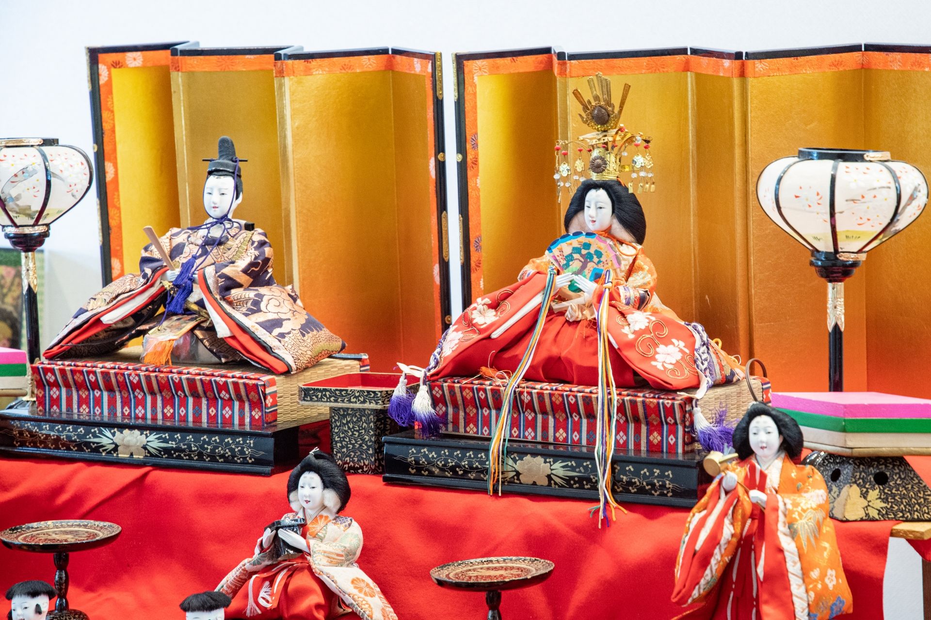 Traditional Japanese Hina doll display with a male and female doll, golden screens, and lanterns.